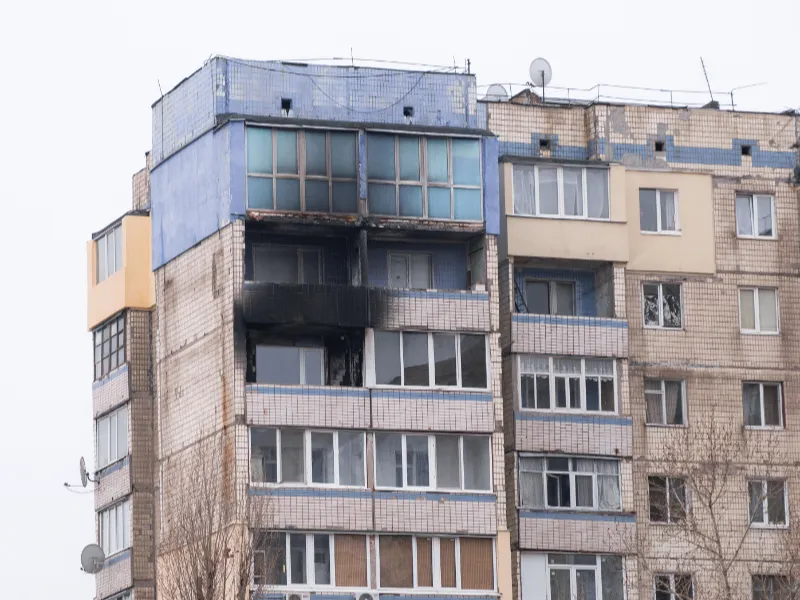 Upper floors of an apartment building with visible fire damage and blackened walls on one balcony.